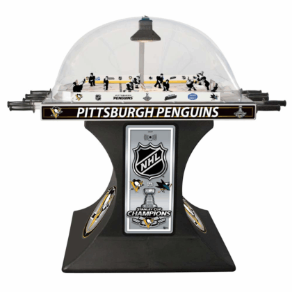 Desktop table hockey game featuring the Pittsburgh Penguins under a clear dome with a commemorative Stanley Cup Champions plaque on a black pedestal