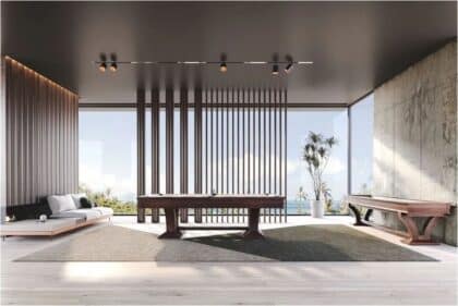 Contemporary living room with a dark wood pool/billiards table, a gray sofa on the left, a bench on the right, vertical slat partition, and a sea view through floor-to-ceiling windows.