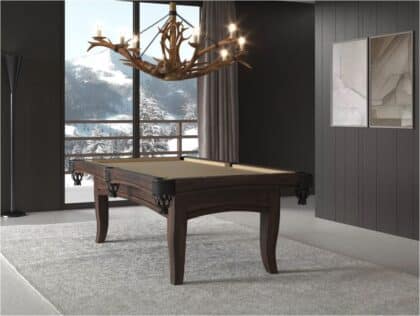 Luxurious dark wood billiards table in a modern room with an antler chandelier and a snowy mountain view outside the window.