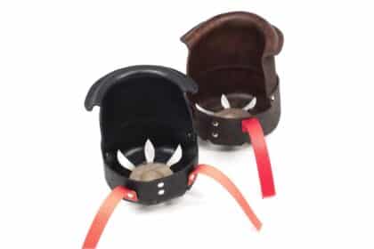 Two leather finger guards (black and brown) with red straps, viewed from above/detached.