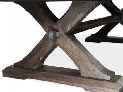 Close-up of a dark wood X-shaped table base with a metal bolt at the joint.