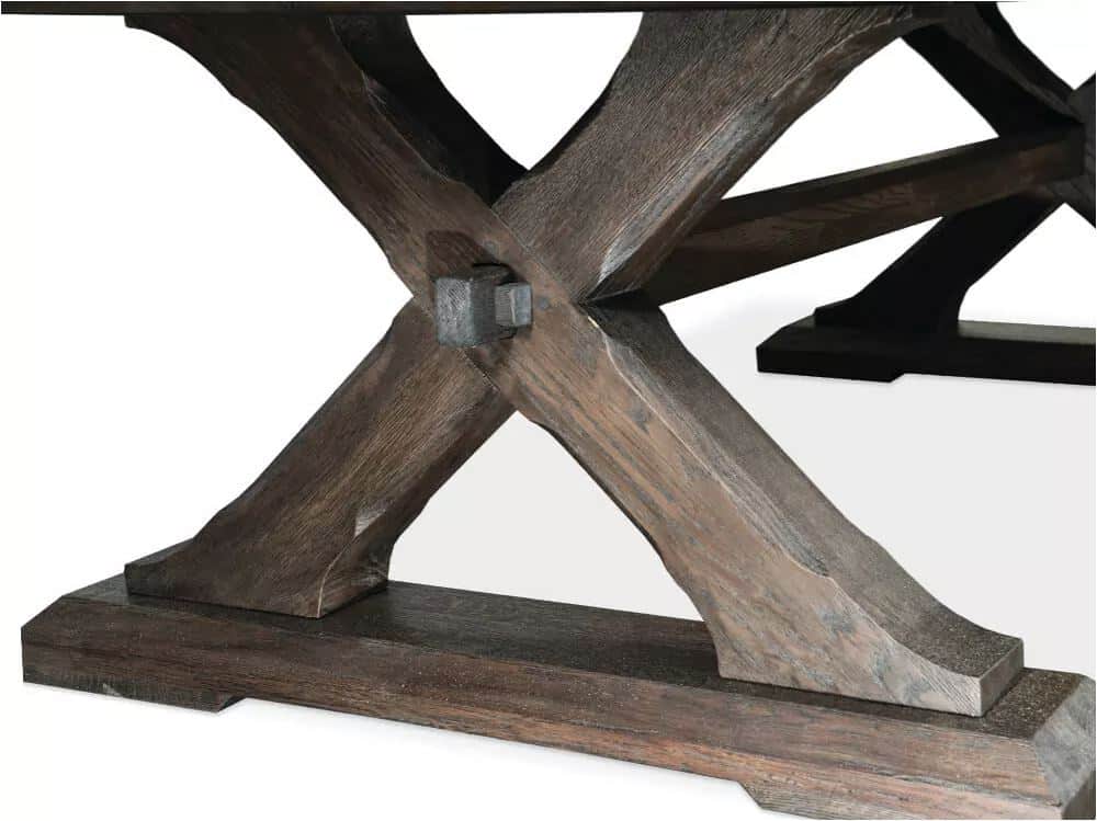 Close-up of a dark wood X-shaped table base with a metal bolt at the joint.