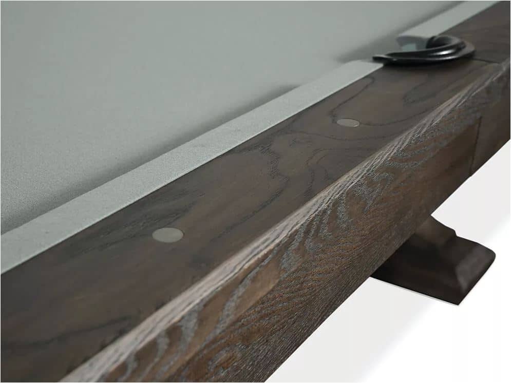 Close-up of a dark wooden shelf edge with a light metal strip and round fasteners, plus a black curved support at the far end.